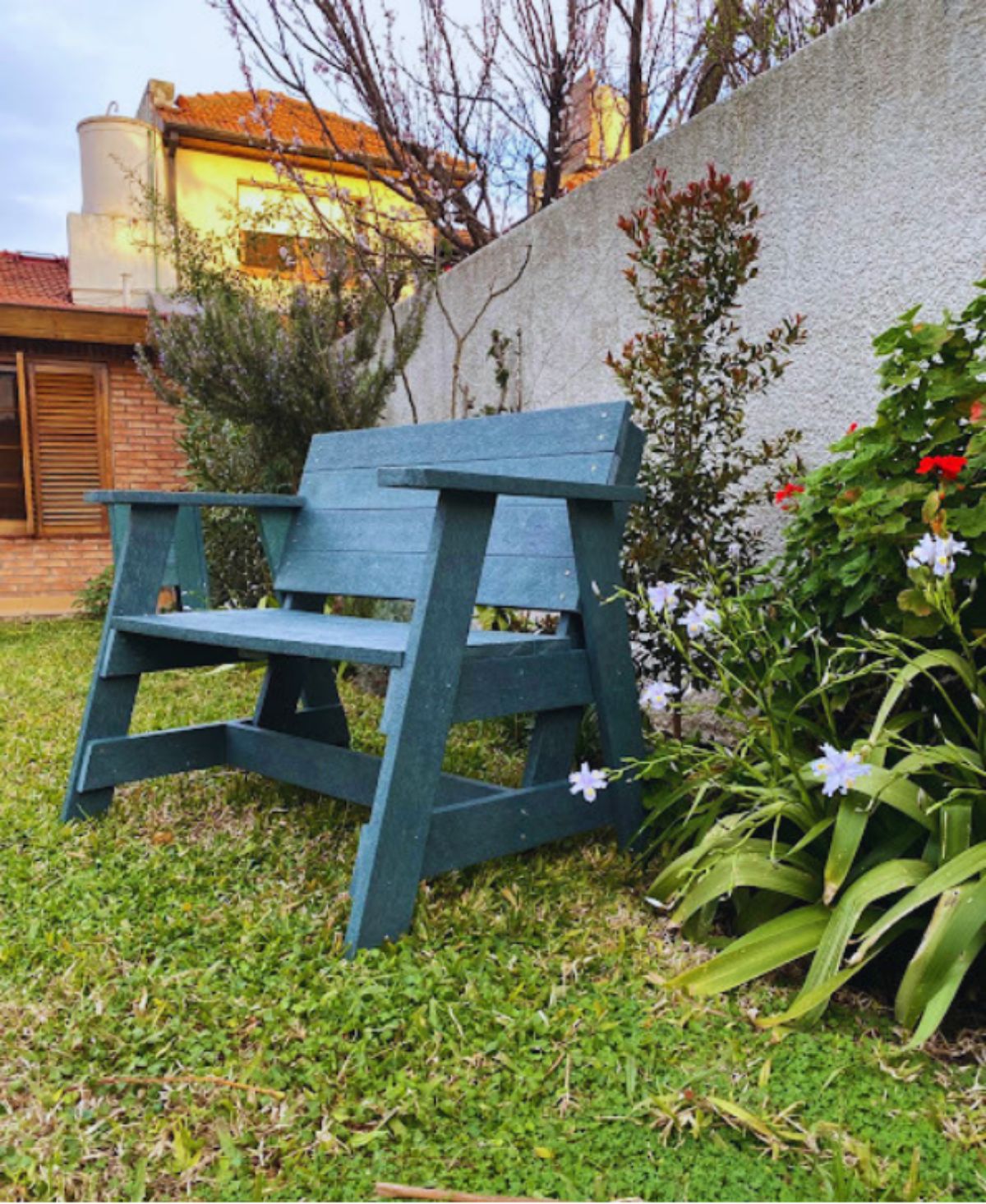 Banco de plaza de perfil, entre las plantas